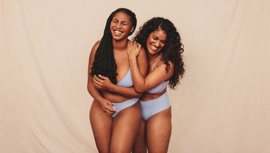 Best friends embracing their natural bodies in a studio