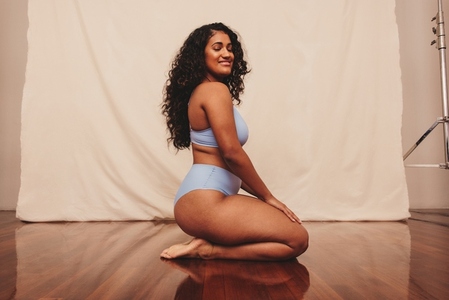 Smiling young woman kneeling in blue underwear