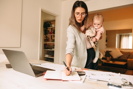 Female designer making notes while holding her baby
