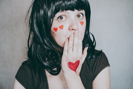 Beautiful portrait of a young woman with red hearts in her face
