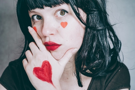 Beautiful portrait of a young woman with red hearts in her face