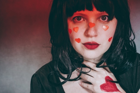 Artistic portrait of a young woman with red heart make up and co