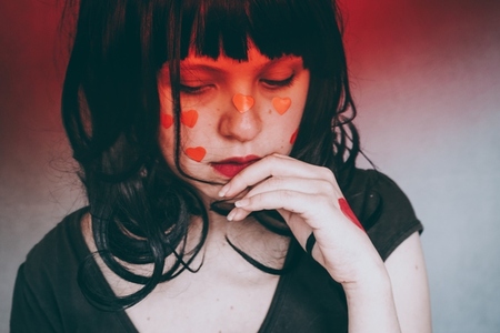 Artistic portrait of a young woman with red heart make up and co