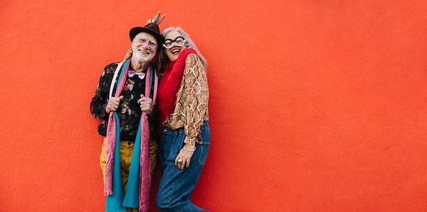Elderly couple laughing happily against a red wall