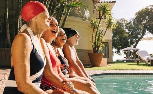 Elderly people laughing happily by the poolside