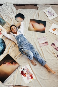 Top view of an artist lying in the middle of her paintings