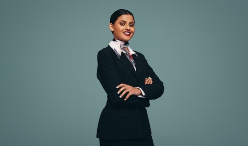 Friendly air hostess smiling at the camera in a studio
