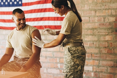 Military doctor administering a vaccine dose to a soldier