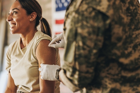 Happy servicewoman smiling cheerfully before an injection