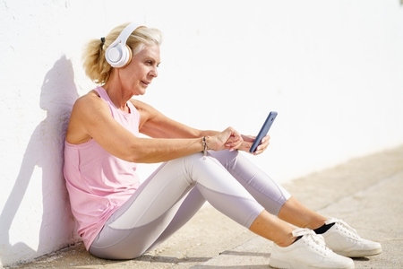 Mature sporty woman taking a break to check a fitness app on her smartphone