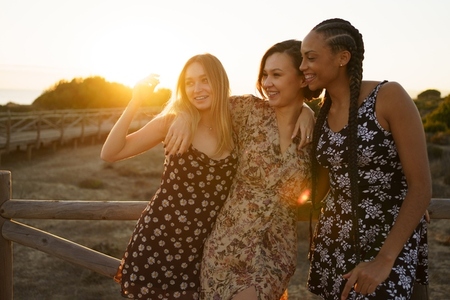 Smiling diverse women embracing on wooden boardwalk