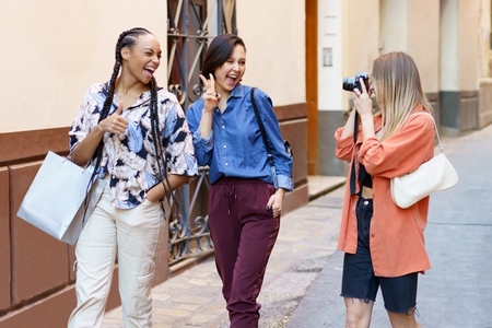 Content lady taking photo of delighted female friends on street