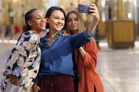 Content young multiracial female tourists smiling at taking selfie on smartphone