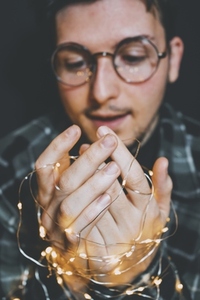 Young man holding christmas lights in his hands