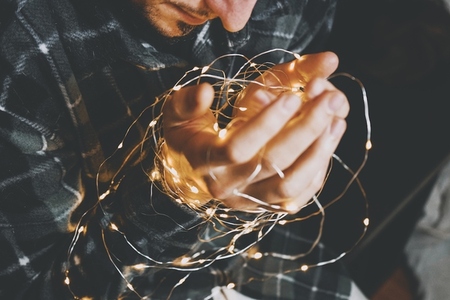 Young man holding christmas lights in his hands