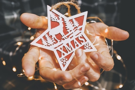 Hands holding a christmas star and fairy lights