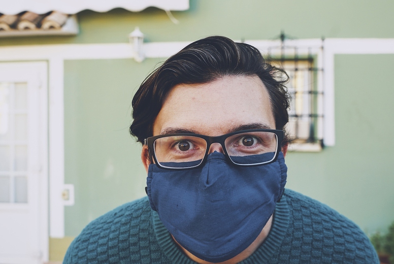 Young man wearing a face mask against a green wall