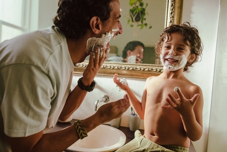 Happy father and son having fun with shaving cream