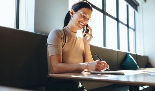 Female entrepreneur writing notes during a phone call