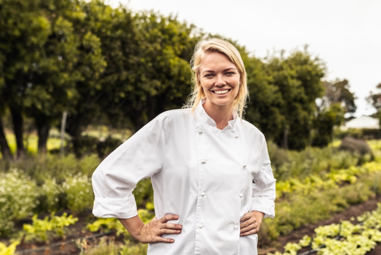 Cheerful young chef smiling at the camera on a farm