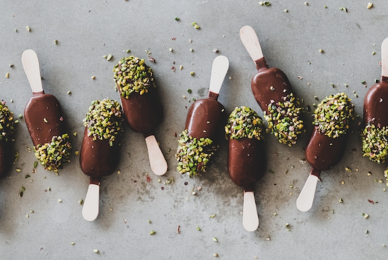 Chocolate glazed ice cream pops over grey background, wide composition