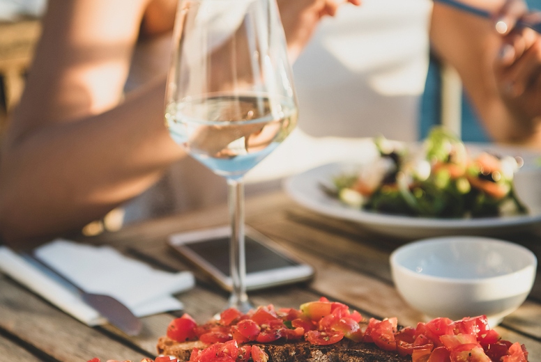 Young woman eating salad and brischetta in Italy in summer