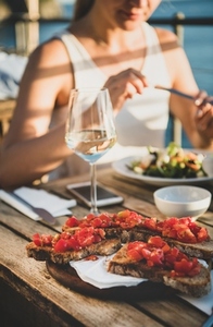 Young woman eating salad and brischetta in Italy in summer