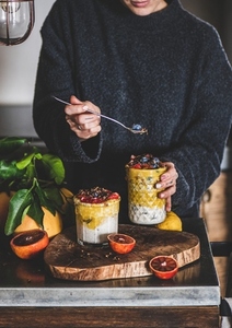 Woman eating muesli with mango smoothie  granola and berries