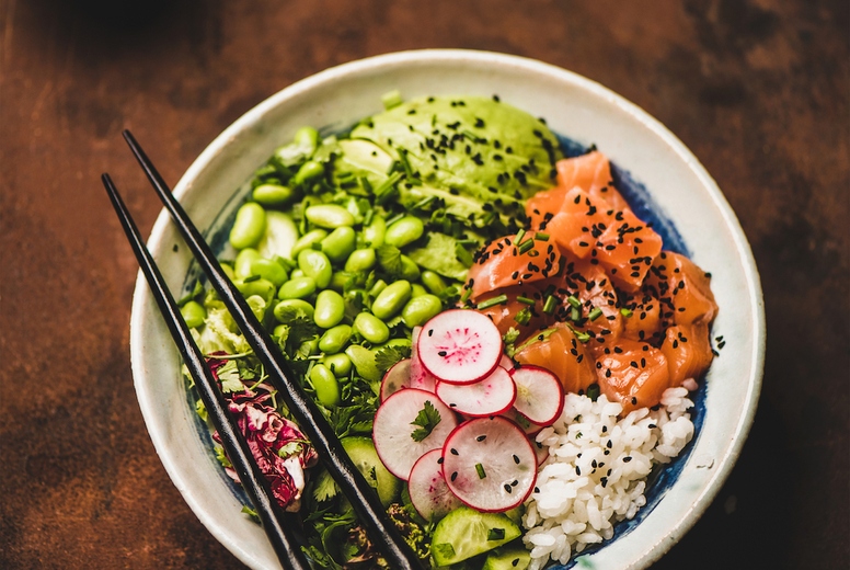 Healthy salmon poke bowl with vegetables, greens, rice, soy sauce