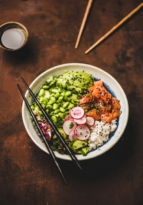Healthy salmon poke bowl with vegetables  greens  rice  soy sauce