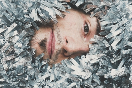 Young male surrounded by silver garland at christmas