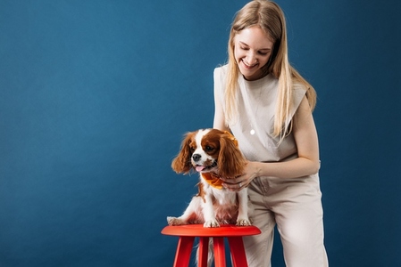 Pet owner standing in the studio  Little dog sitting on a red chair