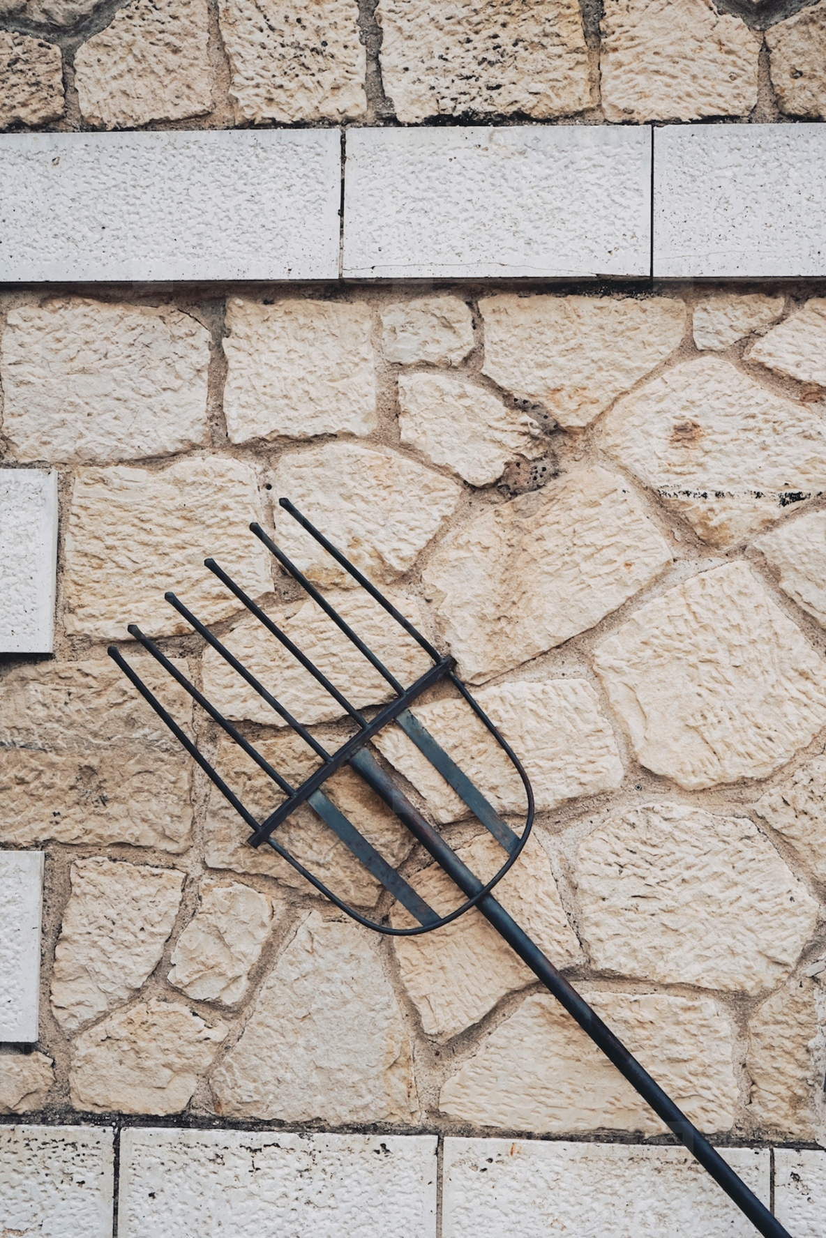 Old pitchfork as decoration in a stone wall