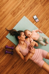 Top view of a mom lying on an exercise mat with her baby