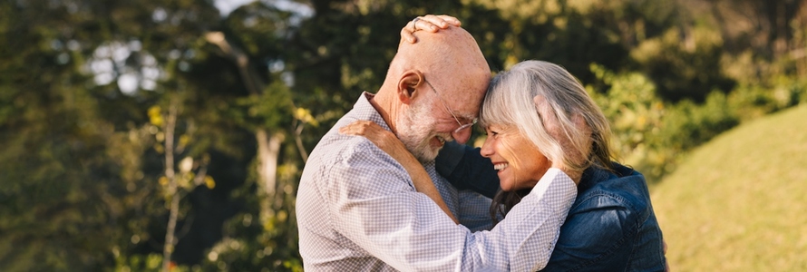 Elderly couple touching their heads together in a park