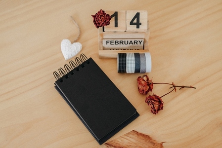 Wooden calendar on February 14 with roses and heart