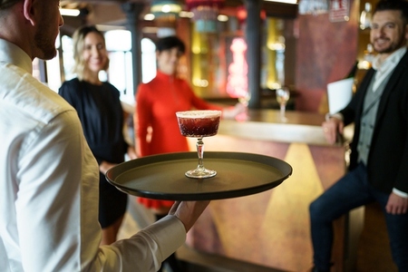 Waiter serving a cocktail for elegant clients in a nice bar