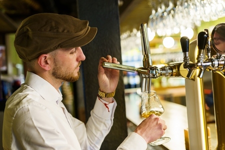 Waiter pouring beer in glass in a bar