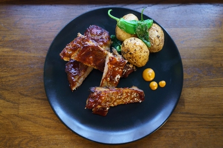 Plate with fried ribs and potatoes on wooden table