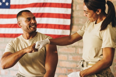 Happy young soldier fist bumping a nurse after getting vaccinated