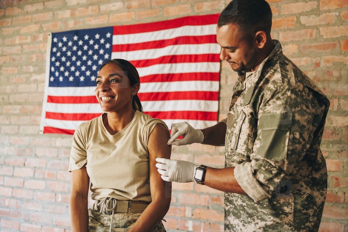 Male nurse rubbing a soldiers arm with cotton before an injection