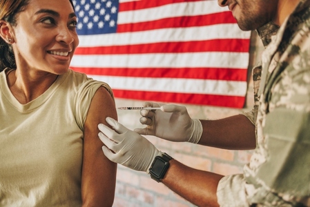 Smiling servicewoman receiving an injection in the army hospital
