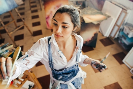 Young artist painting with a paintbrush in her studio