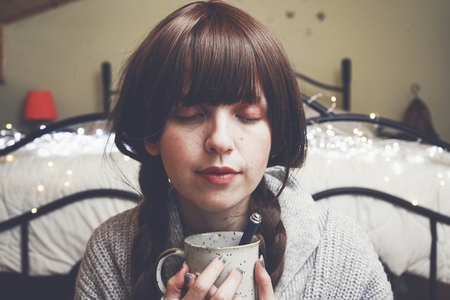 Young and dreamy woman enjoying a cup of coffee