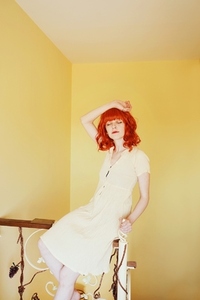 Young redhead woman with a yellow dress in a yellow room