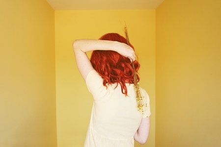 Young redhead woman with a yellow dress in a yellow room