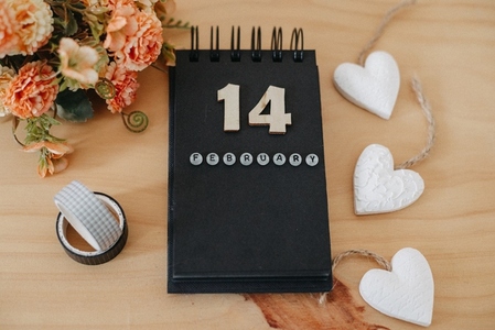 Wooden calendar on February 14 with roses and heart