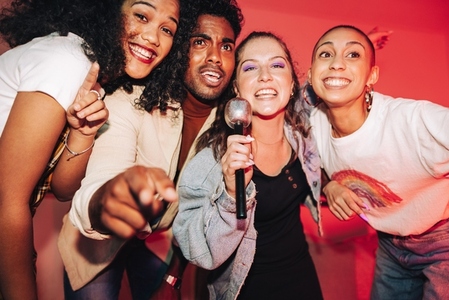 Happy friends singing into a mic on karaoke night