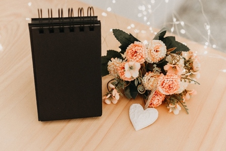 notebook with black sheets with copy space  a bouquet of flowers and a white heart