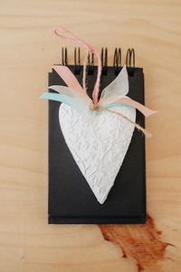 notebook with black sheets on a wooden table with a white heart